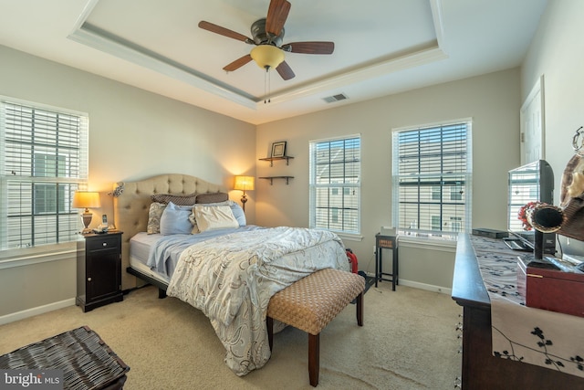 bedroom featuring light carpet, a tray ceiling, and baseboards