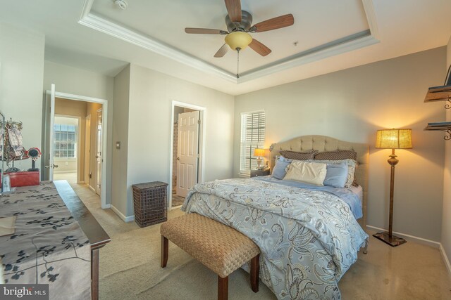 carpeted bedroom with a raised ceiling, baseboards, ornamental molding, and a ceiling fan