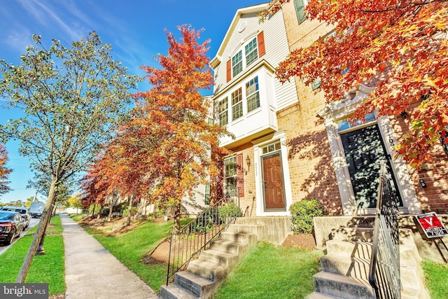multi unit property with brick siding and a front yard