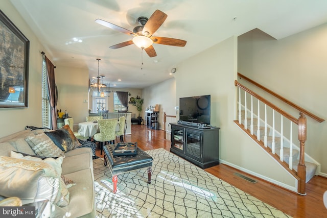 living room with wood finished floors, ceiling fan, stairway, and baseboards