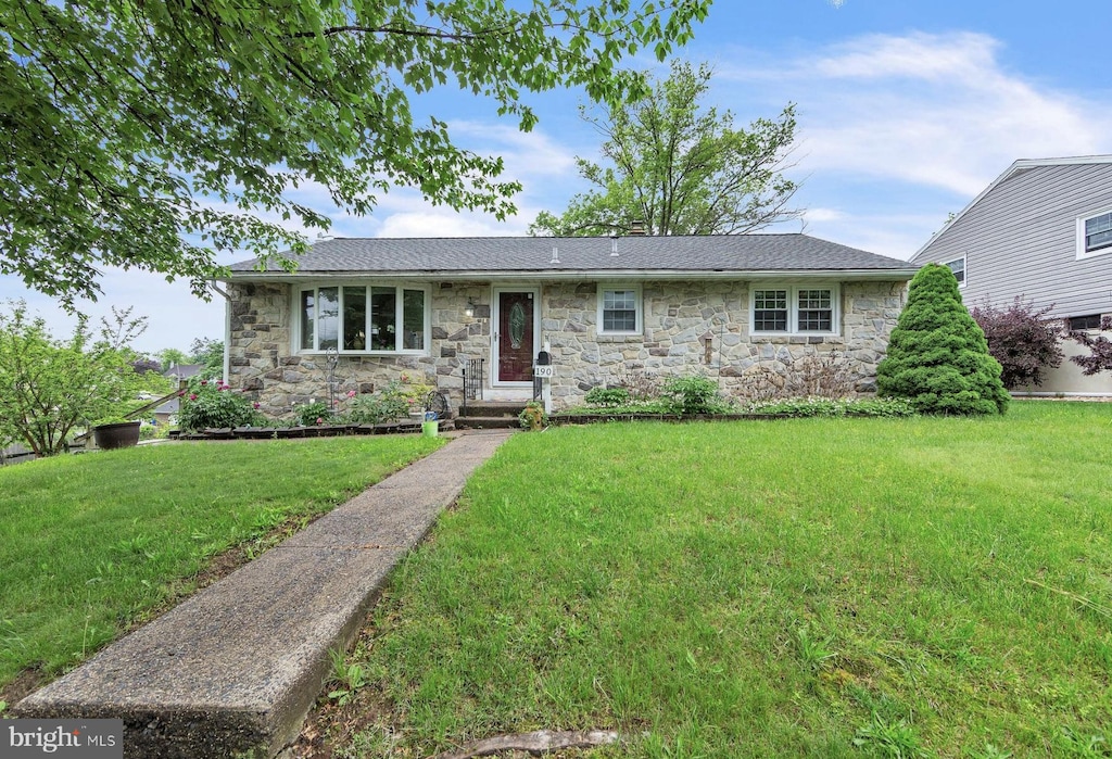 view of front of property featuring stone siding and a front yard