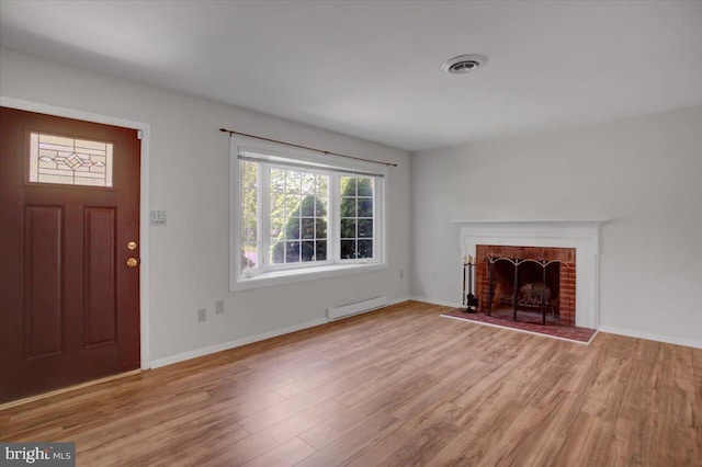 102 Andover Ct, Frederick, MD 21702 - unfurnished living room featuring wood finished floors, baseboard heating, a brick fireplace, and baseboards