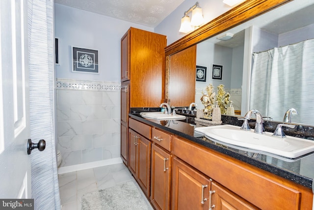 1765 Stone Dr, Huntingtown, MD 20639 - full bath featuring marble look tiles, double vanity, and toilet