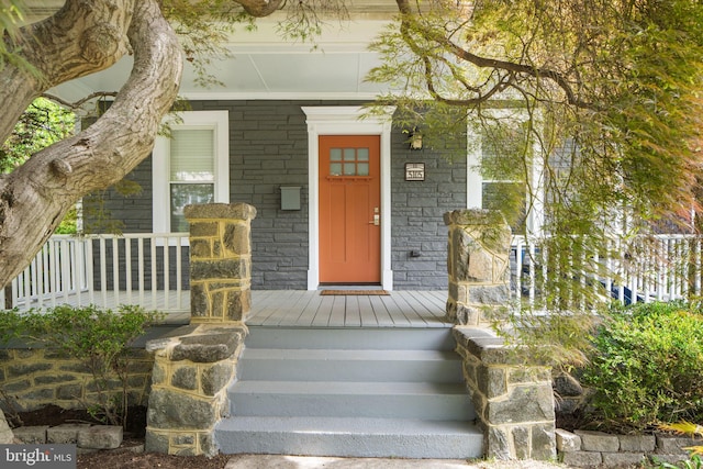 doorway to property featuring covered porch and stone siding