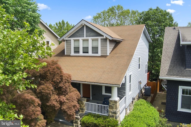 view of front of house featuring a porch, roof with shingles, and central AC
