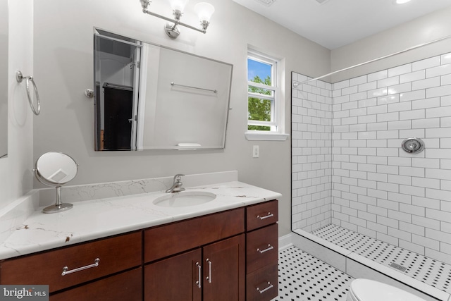 bathroom featuring a tile shower, vanity, and toilet