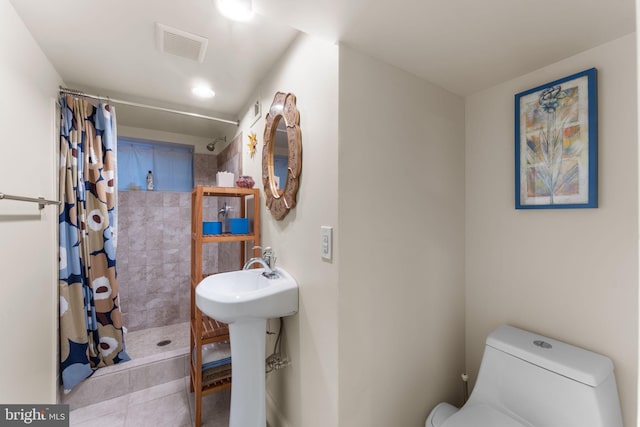 full bath with toilet, tiled shower, and tile patterned flooring