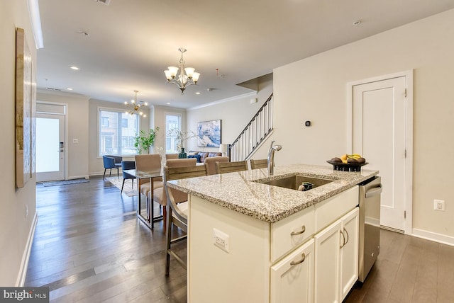 kitchen featuring a sink, a chandelier, dark wood finished floors, a kitchen island with sink, and ornamental molding