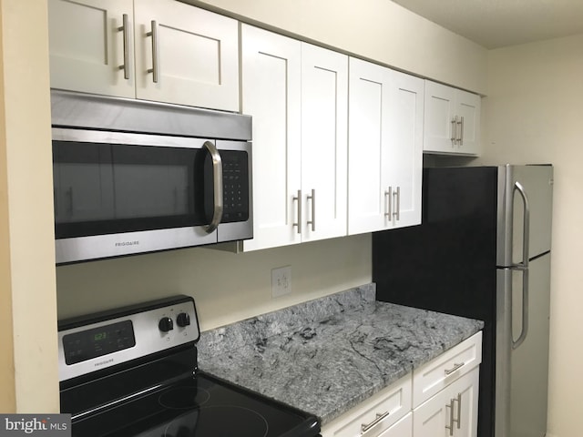 kitchen with stainless steel appliances, white cabinets, and light stone counters