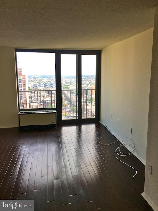 empty room featuring plenty of natural light, dark wood-style flooring, and baseboards