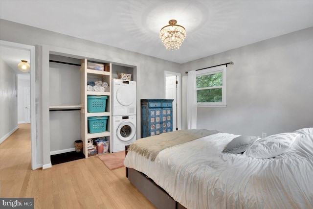 907 Sterling Ct, Herndon, VA 20170 - bedroom with stacked washer and clothes dryer, wood finished floors, a chandelier, and baseboards