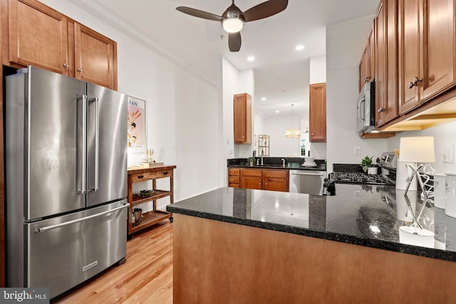 kitchen with stainless steel appliances, ceiling fan, a peninsula, light wood-style flooring, and brown cabinets