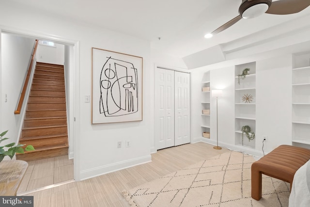 sitting room with built in features, stairway, ceiling fan, and baseboards