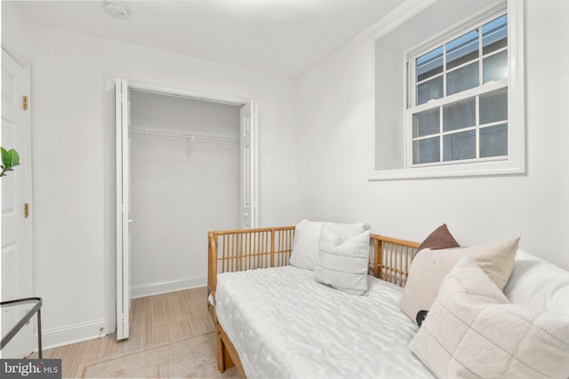 bedroom with wood finished floors, a closet, and baseboards