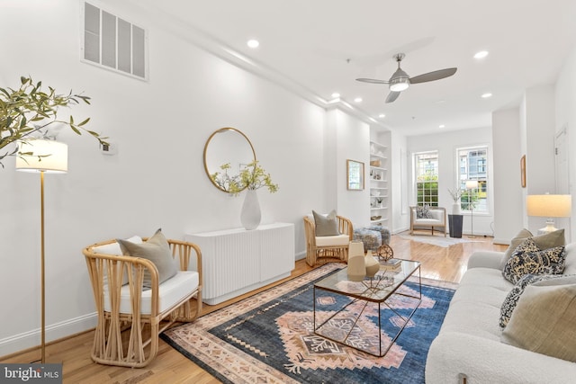 living area with built in features, wood finished floors, ceiling fan, recessed lighting, and baseboards