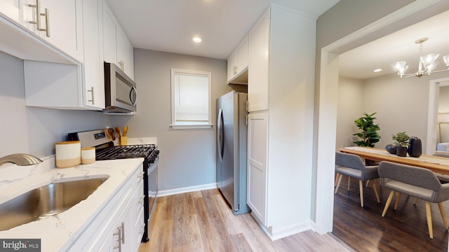 724 Overbrook Rd, Baltimore, MD 21212 - kitchen featuring appliances with stainless steel finishes, a sink, white cabinets, light wood-style floors, and baseboards