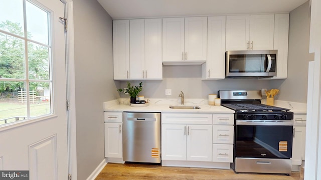 724 Overbrook Rd, Baltimore, MD 21212 - kitchen with stainless steel appliances, a sink, light stone countertops, white cabinets, and light wood finished floors