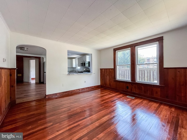 1021 Park Ave, Annapolis, MD 21403 - empty room featuring wainscoting, arched walkways, wooden walls, and hardwood / wood-style flooring