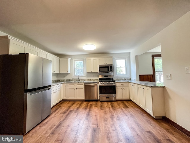 1021 Park Ave, Annapolis, MD 21403 - kitchen featuring stainless steel appliances, wood finished floors, white cabinets, and light stone counters