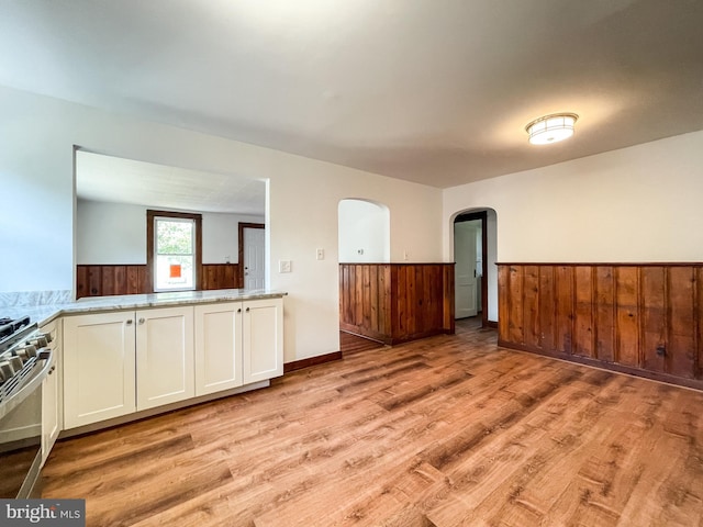 1021 Park Ave, Annapolis, MD 21403 - spare room featuring light wood finished floors, wainscoting, arched walkways, and wooden walls
