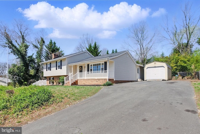 tri-level home with covered porch, an outdoor structure, driveway, a chimney, and a detached garage