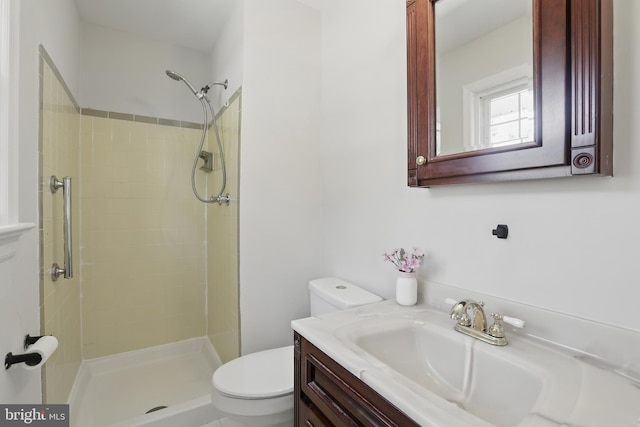 full bath featuring toilet, a tile shower, and vanity