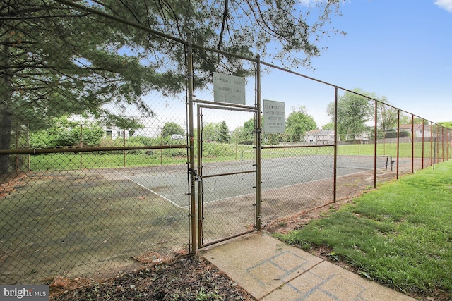 view of tennis court with a gate and fence