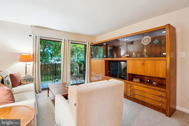 living area featuring light colored carpet and baseboards