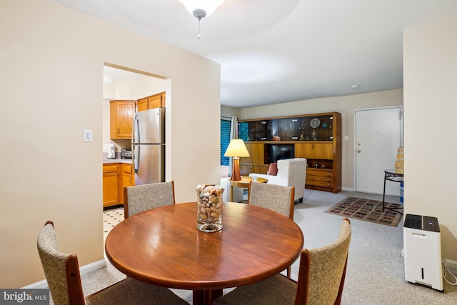 dining space featuring baseboards and light carpet