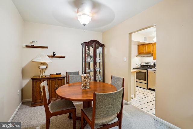 dining space with light carpet, a ceiling fan, and baseboards