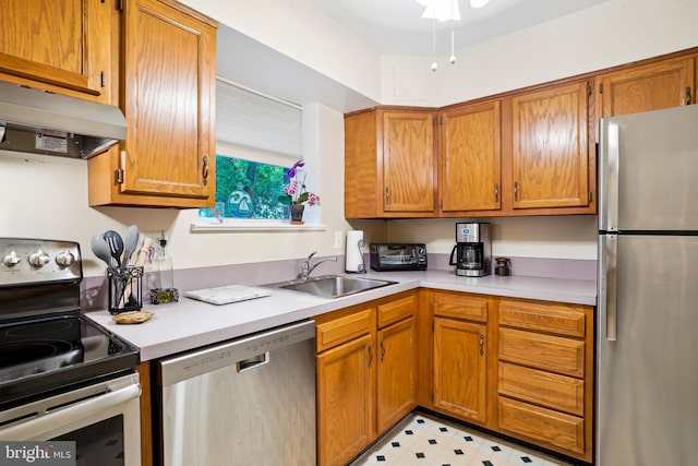 kitchen featuring stainless steel appliances, under cabinet range hood, a sink, light countertops, and brown cabinetry
