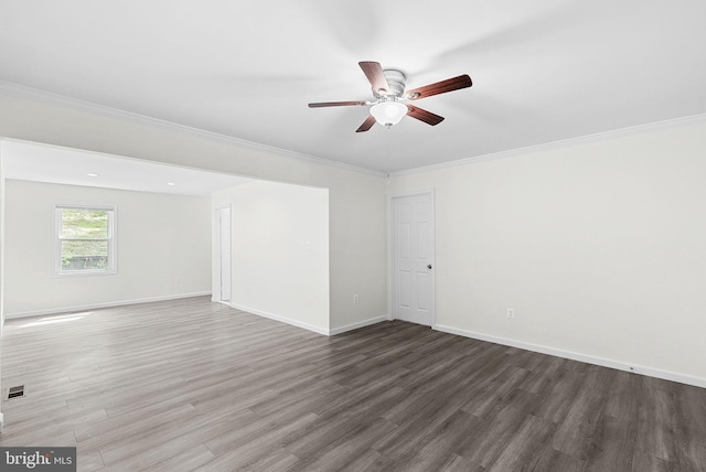 unfurnished room featuring wood finished floors, a ceiling fan, baseboards, and crown molding