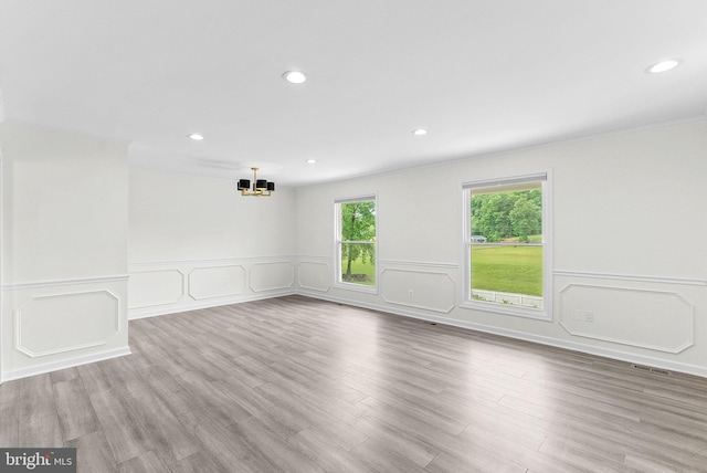 spare room with a chandelier, recessed lighting, wainscoting, and wood finished floors