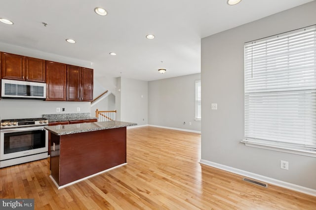 kitchen featuring gas range oven, recessed lighting, light wood-style flooring, baseboards, and a kitchen island