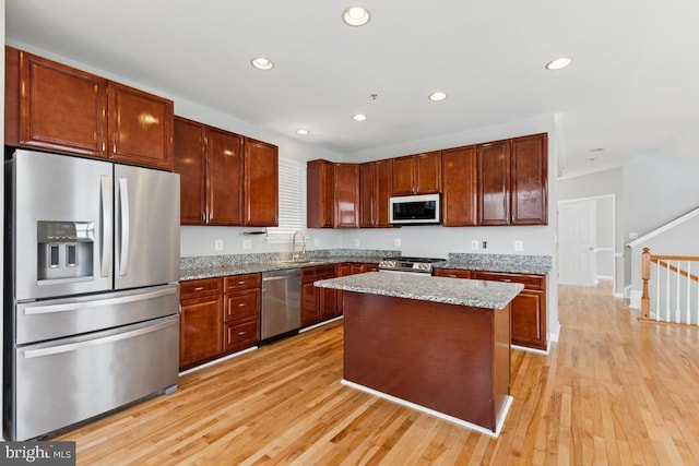 kitchen with appliances with stainless steel finishes, a sink, light wood-type flooring, recessed lighting, and ornamental molding