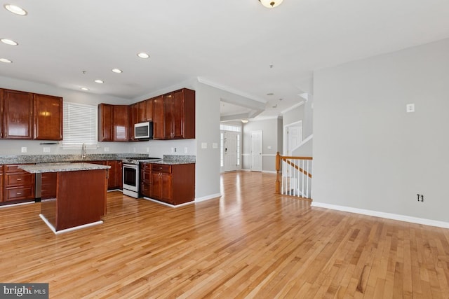 kitchen featuring stainless steel appliances, open floor plan, light wood-style flooring, recessed lighting, and a center island