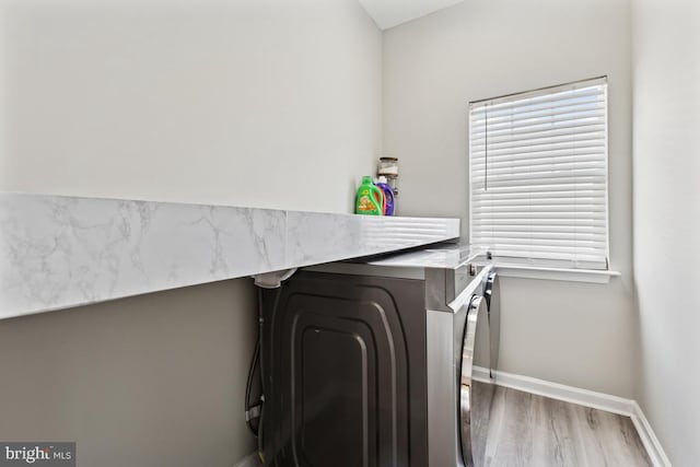 laundry room featuring baseboards, wood finished floors, and washer / clothes dryer