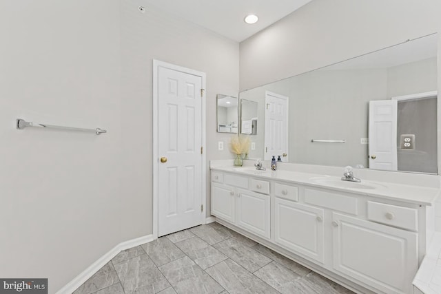 bathroom with double vanity, baseboards, and marble finish floors