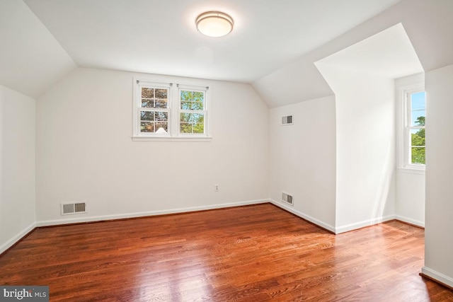 additional living space with vaulted ceiling, healthy amount of natural light, wood finished floors, and baseboards