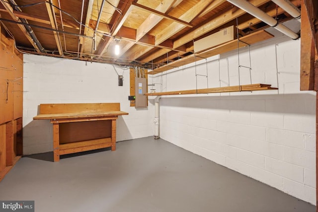 unfinished below grade area with a workshop area, electric panel, and concrete block wall