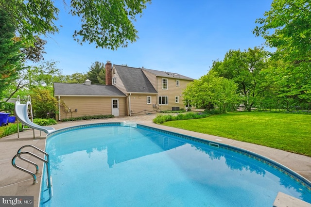 swimming pool with a water slide, a yard, and a patio area