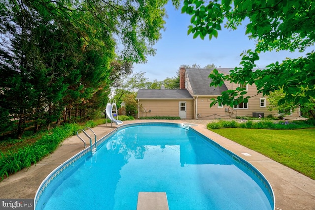 swimming pool featuring a water slide, a lawn, and a diving board