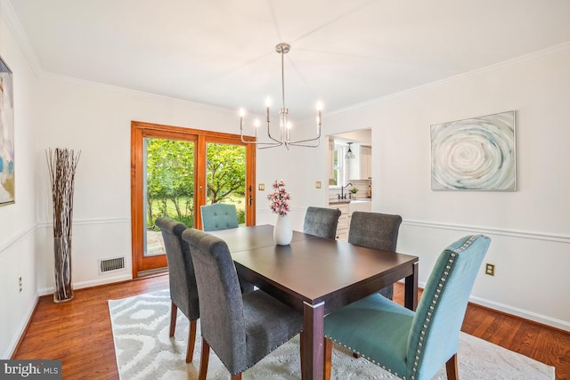 dining area with a chandelier, wood finished floors, ornamental molding, and baseboards
