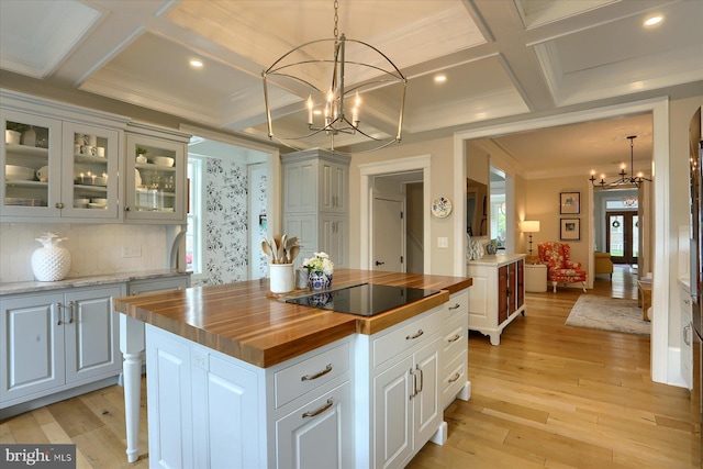 65 S College St, Carlisle, PA 17013 - kitchen featuring wooden counters, a chandelier, coffered ceiling, light wood finished floors, and glass insert cabinets
