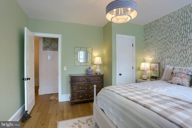 65 S College St, Carlisle, PA 17013 - bedroom with wallpapered walls, wood finished floors, baseboards, a chandelier, and an accent wall