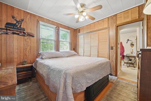 bedroom with wood walls, a closet, wood finished floors, and ceiling fan