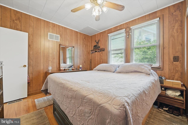 bedroom with wood finished floors, wooden walls, and ceiling fan