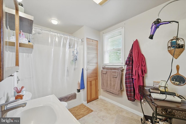 bathroom featuring a sink, a shower with shower curtain, and baseboards
