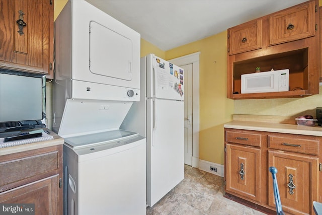 washroom with stacked washer and clothes dryer and baseboards