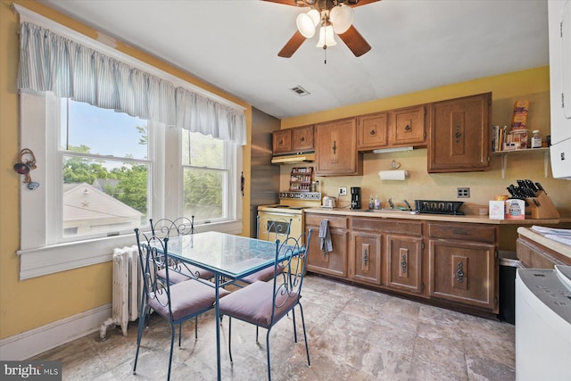 kitchen with under cabinet range hood, ceiling fan, white electric range oven, radiator heating unit, and brown cabinets